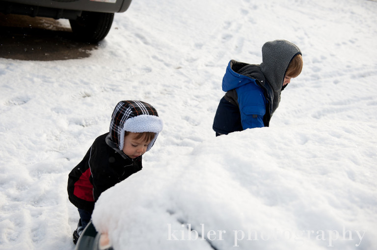 boys cleaning snow off of car