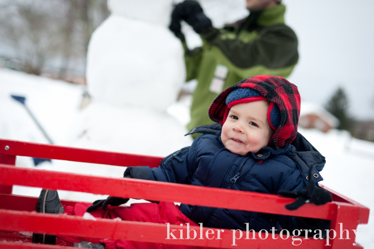 cute baby boy in his red wagon in the snow photo