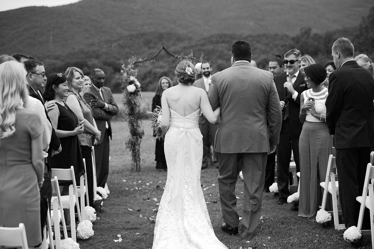 black and white photo of father walking bride down the aisle
