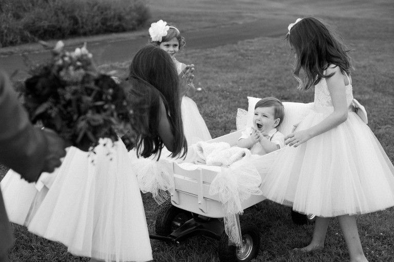 ring bearer surrounded by flower girls, black and white photo