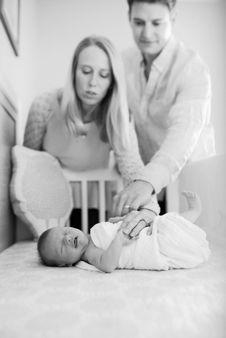 new parents comforting baby boy in his crib during Virginia newborn session