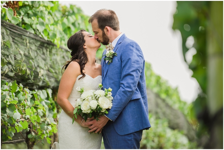Bride and groom kissing in the vines by Early Mountain Wedding photographer